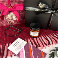 Gift set with a spiced orange candle, box, and decorative item on a red blanket