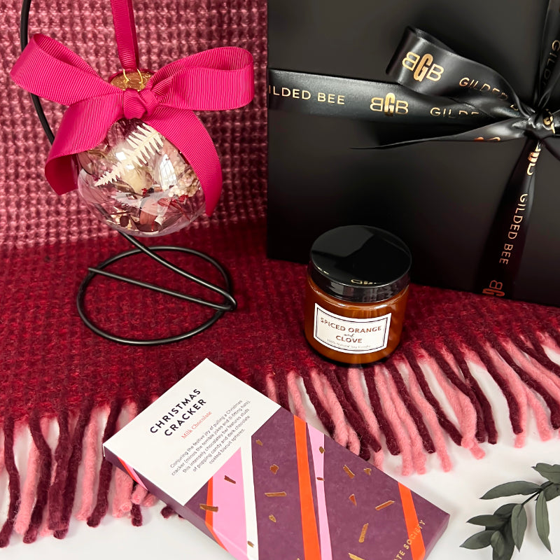 Gift set with a candle card, and decorative item on a red blanket