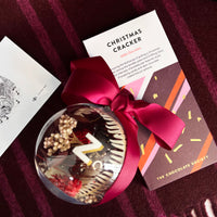 Decorative chocolate cracker with a red ribbon on a dark fabric background