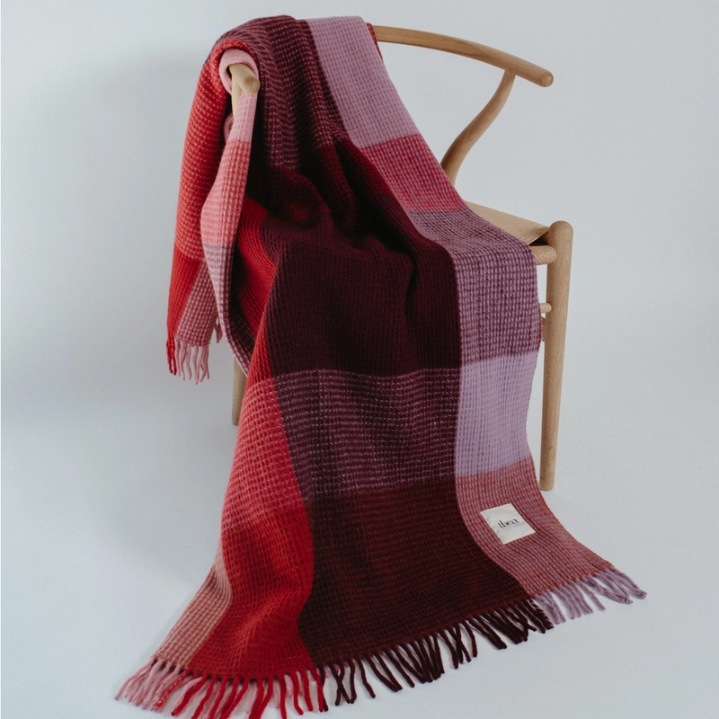burgundy and purple plaid blanket draped over a wooden chair on a white background