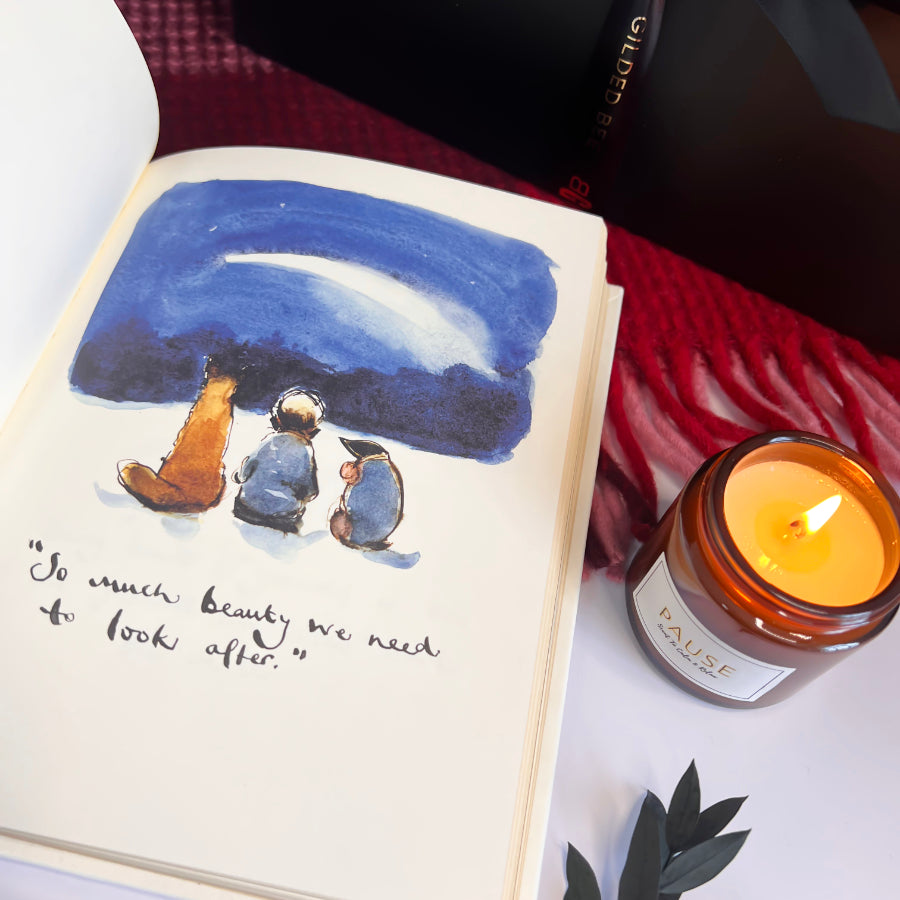 Open book with illustration of two figures under a blue sky, next to a lit candle labeled 'Pause'.