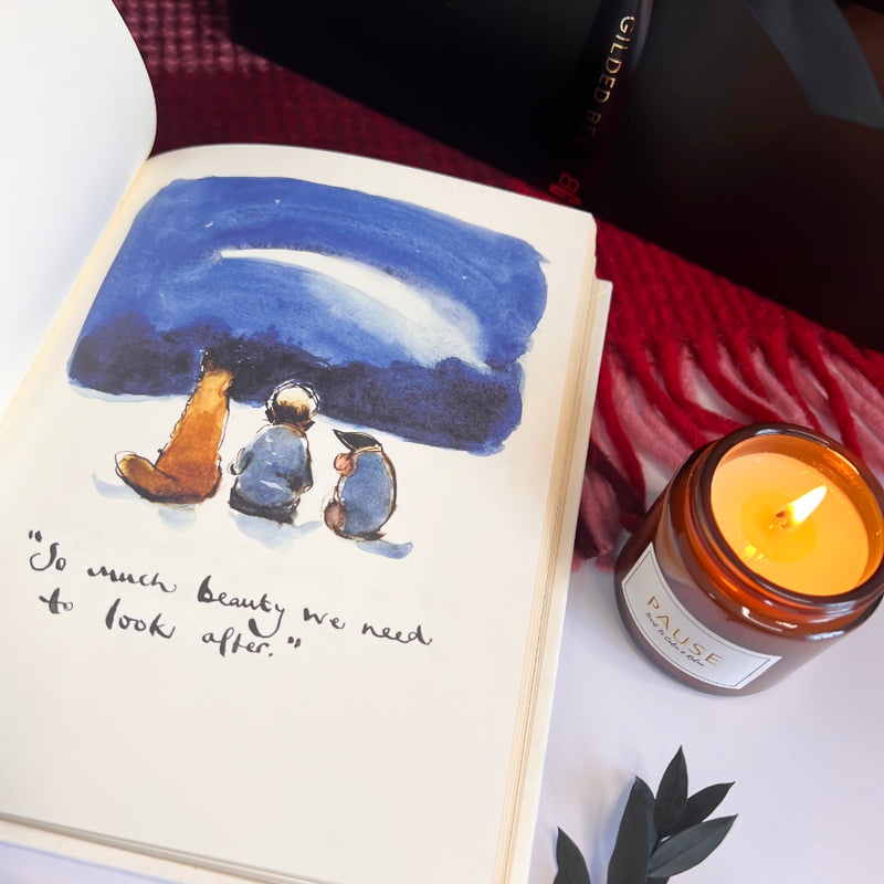 Open book with illustration of two figures under a blue sky, next to a lit candle labeled 'Pause'.