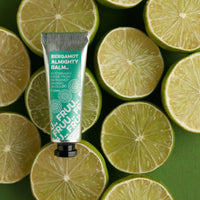 A tube of Bergamot Almighty Balm by Fruu positioned against a background of lime slices.
