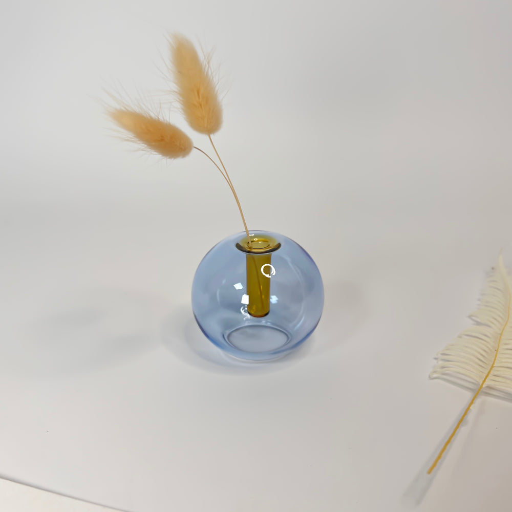 Blue glass vase with dried pampas grass against a white background
