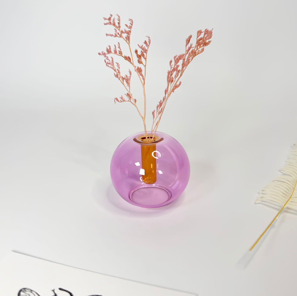 lilac glass vase with dried plants on a white surface