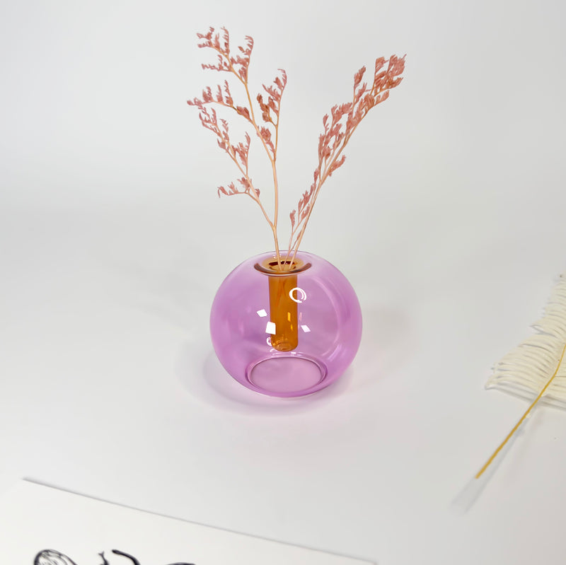 lilac glass vase with dried plants on a white surface