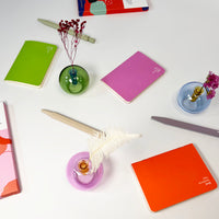 Colorful notebooks and small vases on a white surface