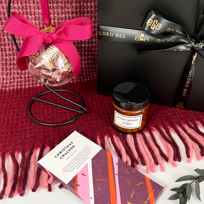 Gift set with a candle card, and decorative item on a red blanket