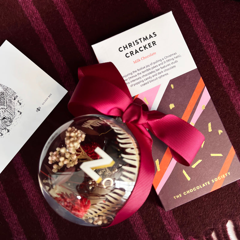 Decorative chocolate cracker with a red ribbon on a dark fabric background