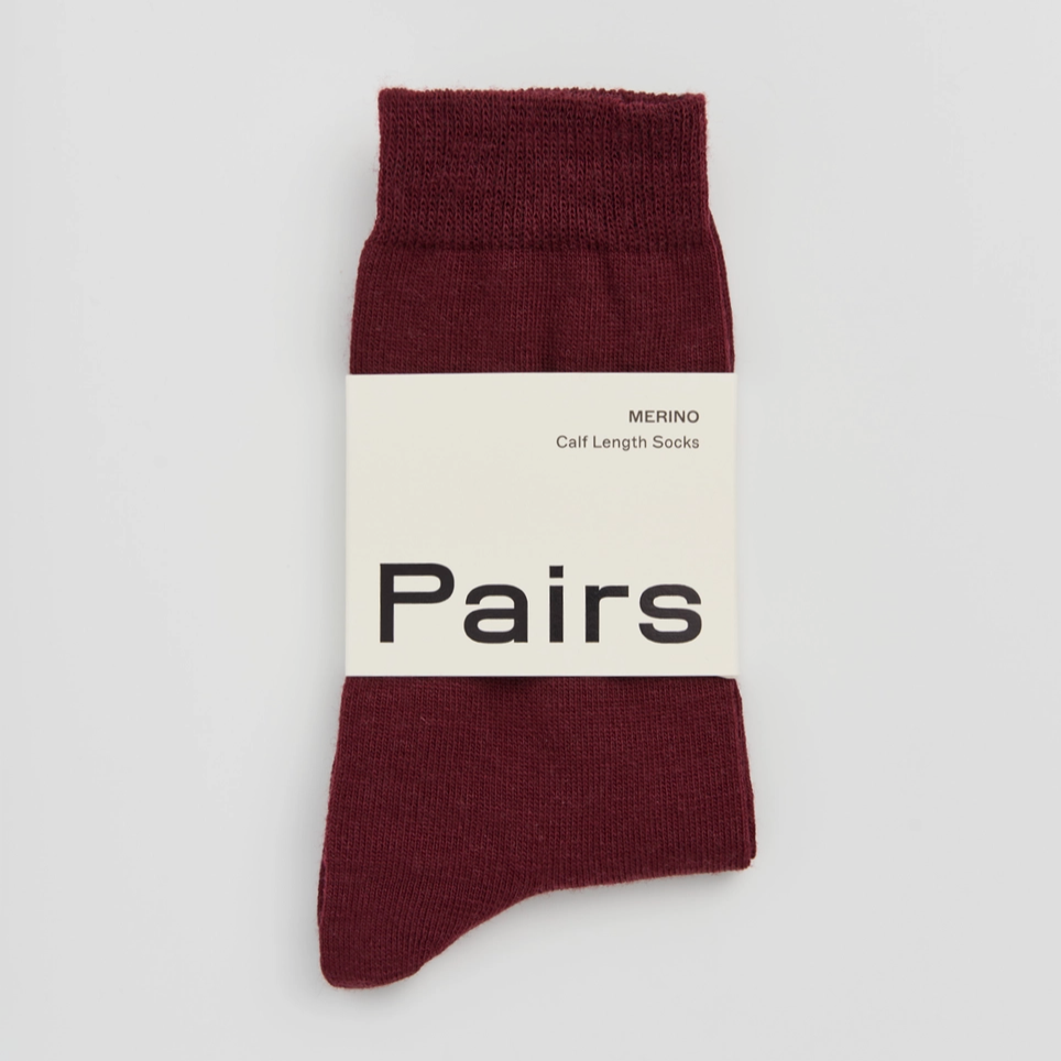 Burgundy sock with a white label on a light grey background