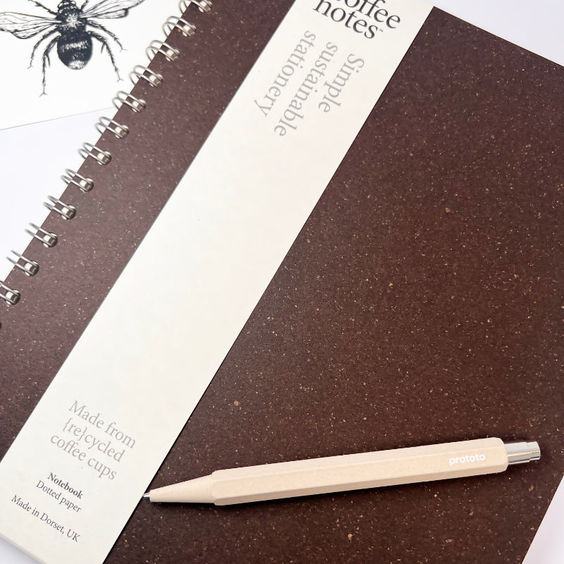 Spiral-bound notebook with a pen on a white background and bee gift card