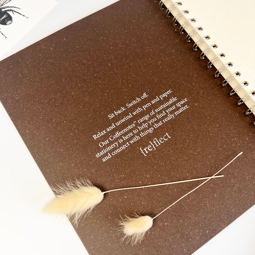 Brown notebook with text and decorative grasses on a white background