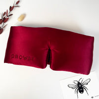 burgundy satin eye mask with 'Drowsy' branding on a white background