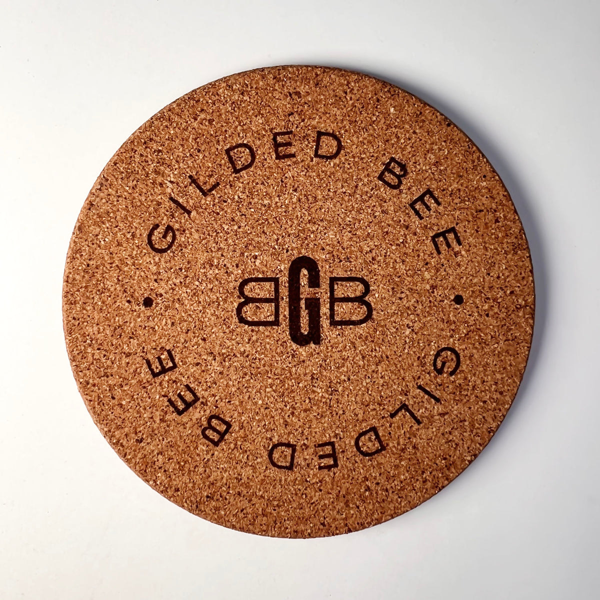 Cork coaster branded with Gilded Bee on white background