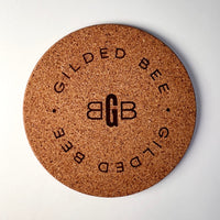 Cork coaster branded with Gilded Bee on white background
