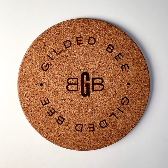 Cork coaster branded with Gilded Bee on white background