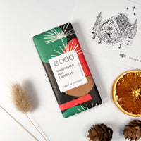 Chocolate bar with orange slices, pine cones and a gift card with a gingerbread house on