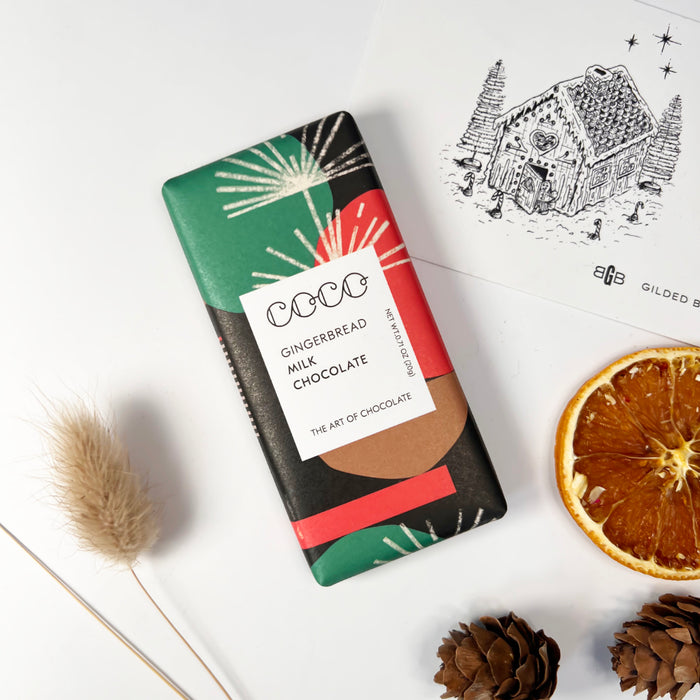 Chocolate bar with orange slices, pine cones and a gift card with a gingerbread house on