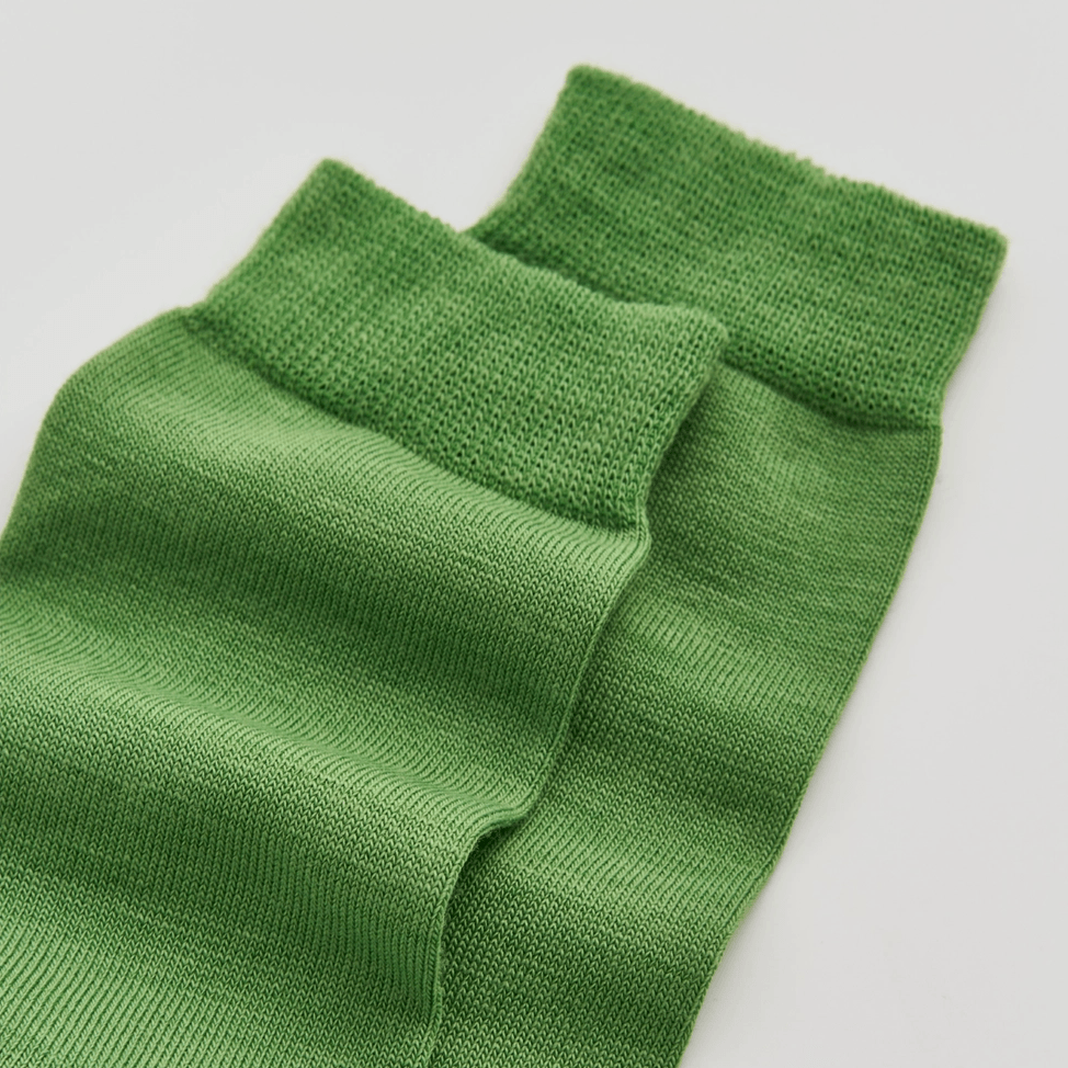 Green knitted socks on a light gray background