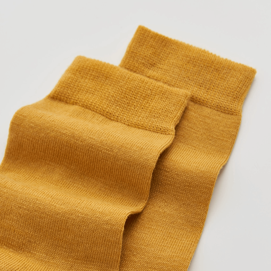 Pair of mustard yellow socks on a light gray background