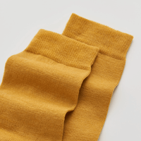 Pair of mustard yellow socks on a light gray background