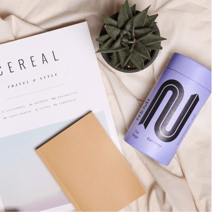 Tea canister with a plant and notebook on a textured surface