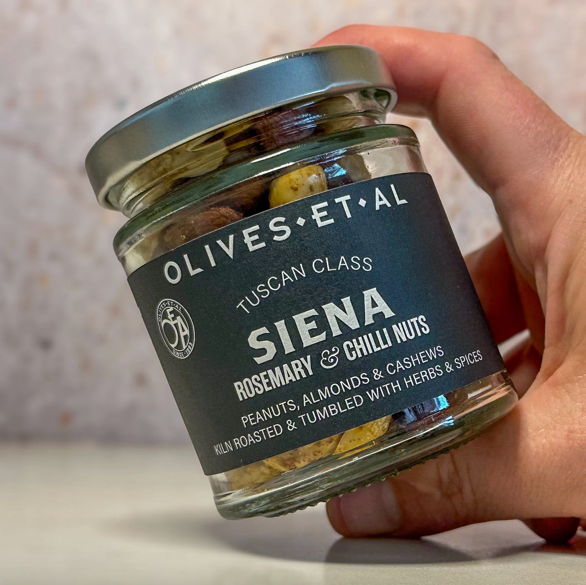 a hand holding a glass jar of nuts