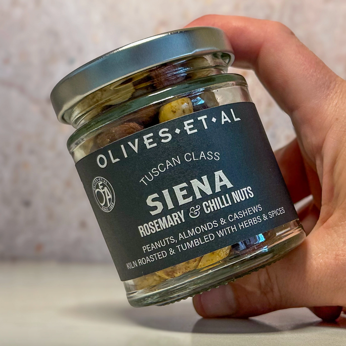 a hand holding a glass jar of nuts