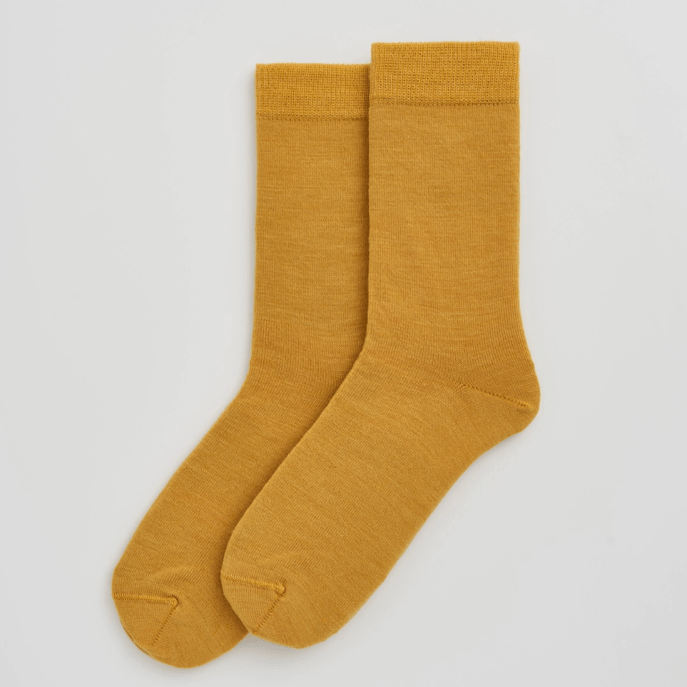 Pair of mustard yellow socks on a light gray background