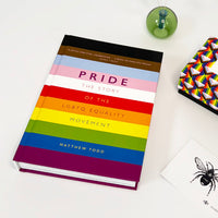 Book titled 'Pride: The Story of the LGBTQ Equality Movement' with a rainbow cover on a white surface.