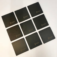 Nine square black slate coasters arranged in a 3x3 grid on a white background. Each coaster features a debossed logo for 'FourStone Bar & Grill' in a light metallic color.