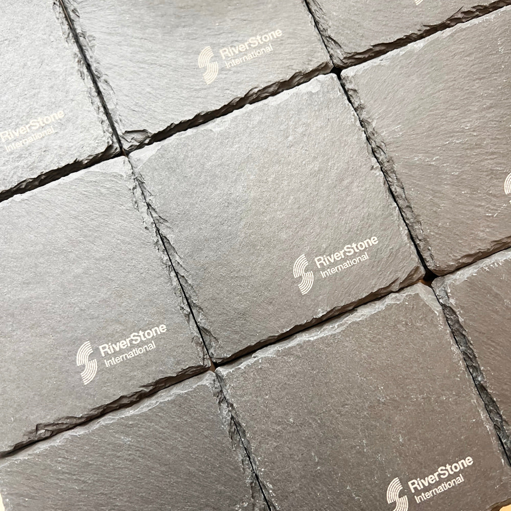 Grey slate coaster arranged in a grid pattern, showing a textured stone surface with visible RiverStone International watermarks.