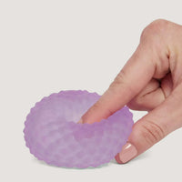 Hand holding a purple silicone cupcake liner against a light gray background