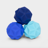 Three faceted geometric stress balls in dark blue, royal blue, and light blue, arranged in a pyramid on a light gray background.