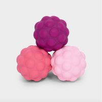 Three raspberry-shaped silicone massage or sensory toys in magenta, coral pink, and light pink, arranged in a pyramid on a light gray background.