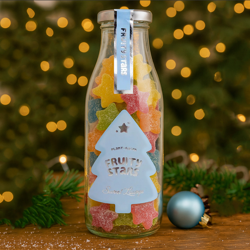 Sweet bottle full of star gummies, with Christmas lights behind.