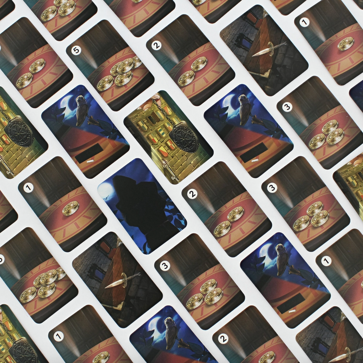 A close-up of a printed card deck or card surface showing multiple illustrated cards arranged in a diagonal grid. The cards feature fantasy-style artwork with dark blue, gold, brown, and black tones, and some cards show coin-like circular objects on a table.