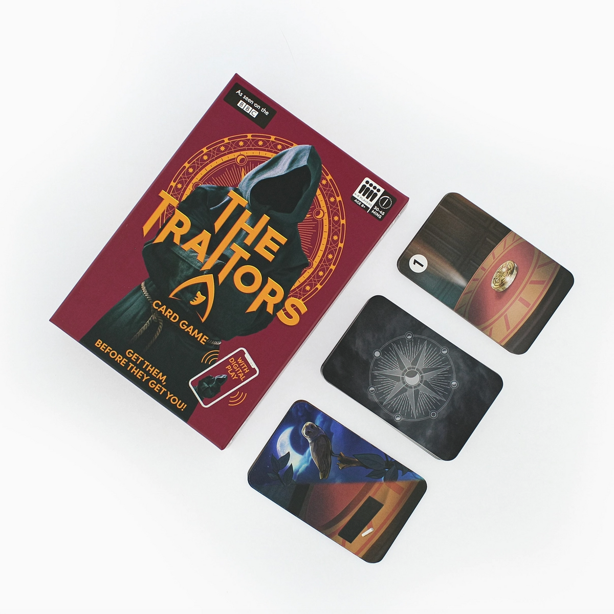 The Traitors card game set displayed on a clean white background, featuring the burgundy and gold game box alongside three illustrated cards.