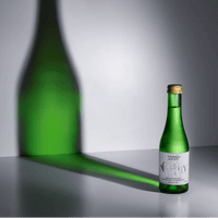 Green bottle with gold cap on a gray surface with a gray background