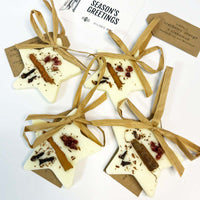 Star-shaped white treats with cinnamon sticks and cranberries, tied with brown ribbons on a white background.